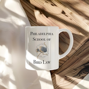 May include: White ceramic mug with a black and white illustration of an ostrich and the text "Philadelphia School of Bird Law".