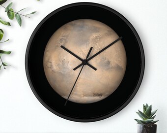 Puede incluir: Un reloj con marco negro con una imagen de planeta rojo en el centro. La esfera del reloj tiene agujas negras y el texto "Clockz" está impreso en la parte inferior.