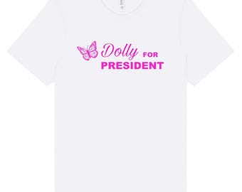 May include: White t-shirt with a pink butterfly and the text "Dolly for President" printed on the front.