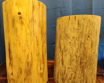 Puede incluir: Dos rodajas de tronco de madera, una de color marrón claro y otra de color marrón oscuro, con un patrón de veta de madera natural. Los troncos se colocan uno al lado del otro sobre una superficie de madera.