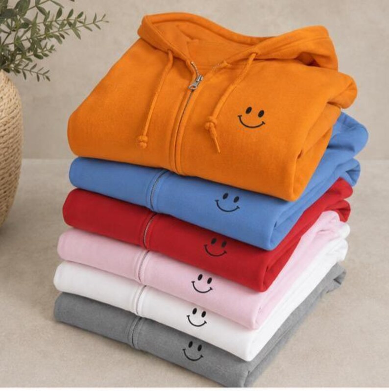Embroidered Chest Graphic Hoodie Smiley Face Design Men Zip Sweatshirt Casual Comfort Wear Minimalist Style Everyday Essential Adjustable Hood Zipper Front Pocket Jacket Cozy Outerwear Year Round Layering Unisex Apparel Simple Smile Happy Unisex Men or Women Zippered Hoodie