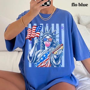 America 250 patriotic tee with Statue of Liberty, flag sunglasses, bubble gum, and hot dog.