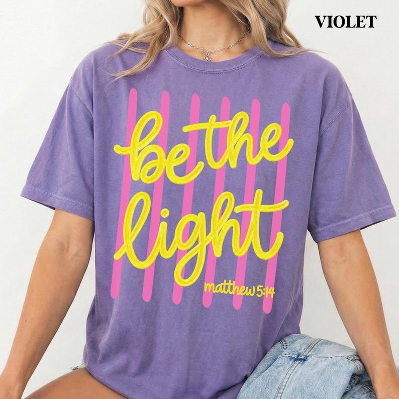 Be the Light faith shirt with modern Christian aesthetic design.
Inspirational Christian graphic tee for women and girls.
Trendy Bible verse Comfort Colors shirt with yellow lettering.
Christian apparel featuring Be the Light inspirational message.
Faith inspired Comfort Colors t-shirt with Christian typography.