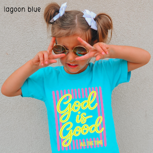 May include: A lagoon blue short-sleeved t-shirt featuring a graphic design with vertical pink stripes and the yellow text "God is Good ALL THE TIME" printed on the front. The shirt is made of a solid lagoon blue fabric with a crew neckline.