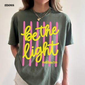 Aesthetic Christian t-shirt featuring Be the Light faith message.