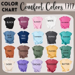 May include: A colour chart of Comfort Colors 1717 t-shirts. The chart shows a range of colours, such as black, berry, blossom, white, and cruchberry. Other colours include blue jean, true navy, chambray, pepper, seafoam, yam, espresso, moss, mustard, light green, ivory, violet, orchid, crissom, and butter.