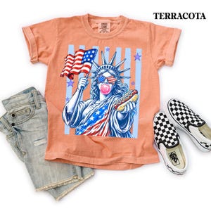 Red white and blue Fourth of July tee with fun Statue of Liberty hot dog design.
