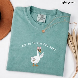 Funny goose illustration with sunglasses and drink printed on comfort colors style aunt shirt.