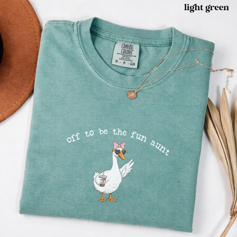 Funny goose illustration with sunglasses and drink printed on comfort colors style aunt shirt.