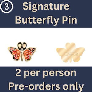 May include: A Signature Butterfly Pin set featuring two pins on a dark blue background with white text. One pin is a butterfly with orange wings and black scissor blades. The other is a gold-toned butterfly shape with the text Crafting with delonda.