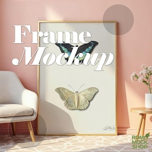 Peut inclure: Une maquette de cadre doré avec un fond blanc et deux papillons. Le papillon du haut est bleu et vert, et le papillon du bas est blanc avec des marques noires. Le cadre est sur un mur rose avec une chaise blanche et une petite table en bois avec un vase blanc et des fleurs.