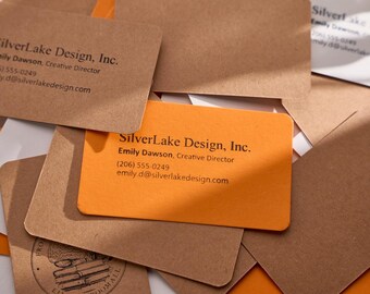 May include: A stack of business cards with a brown and orange color scheme. The text on the cards reads "SilverLake Design, Inc." and includes contact information for Emily Dawson, Creative Director.