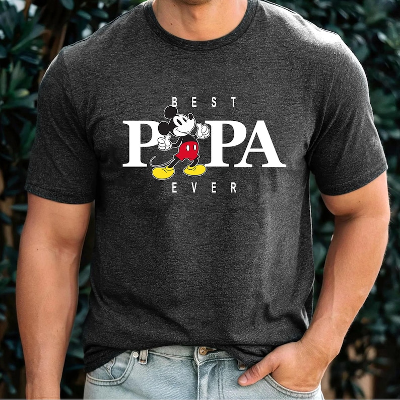 May include: A dark grey t-shirt with a white graphic of Mickey Mouse saying "Best Papa Ever".
