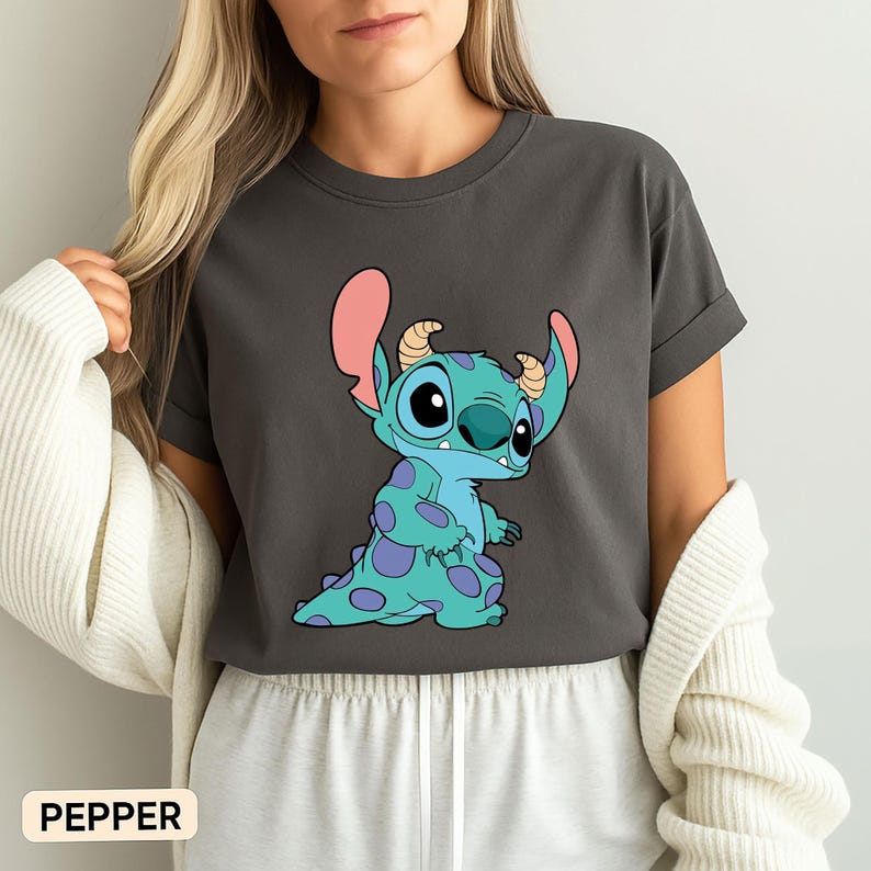 May include: A dark grey t-shirt featuring a blue and pink cartoon character with the text "PEPPER" in the bottom left corner.