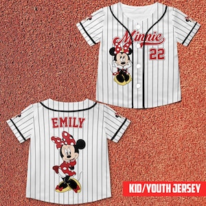 May include: White and black pinstripe baseball jersey featuring Minnie Mouse. The front displays "Minnie" in red script, the number 22, and a Minnie Mouse graphic. The back of the jersey has the name "EMILY" and another Minnie Mouse graphic. The text "KID/YOUTH JERSEY" is in a red box.