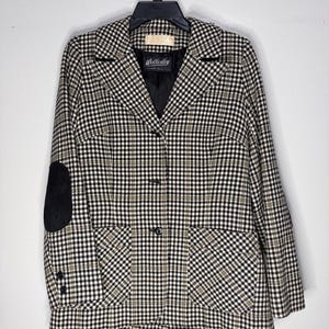 May include: A vintage Wellesley blazer in a black, white, and olive green plaid pattern. The blazer features black elbow patches, two front pockets, and a three-button closure. The label is visible.