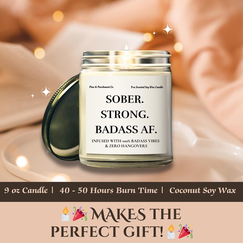 May include: A clear glass jar candle with a silver lid, labeled "SOBER. STRONG. BADASS AF." The candle is infused with "100% BADASS VIBES & ZERO HANGOVERS." It is a 9 oz candle with a burn time of 40-50 hours, made with coconut soy wax.