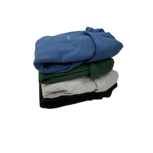 May include: A stack of four folded hoodies in various colors: blue, green, gray, and black. The top blue hoodie has the word "WAZE" embroidered in white on the upper left side. The hoodies are neatly stacked on a white background.