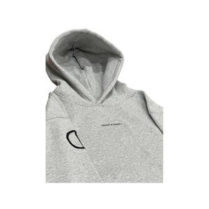 May include: A light gray hoodie with a hood and long sleeves. The hoodie has the phrase "WHAT A DRAG..." embroidered in black on the chest. A black, stylized "D" is embroidered on the left sleeve.