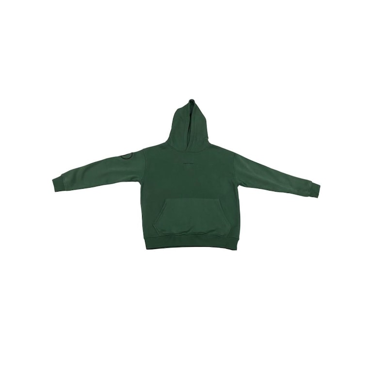 May include: A dark green hoodie with a hood and a front pocket. The long sleeves are spread out. A small circular patch is on the left sleeve. The hoodie is made of a soft material.