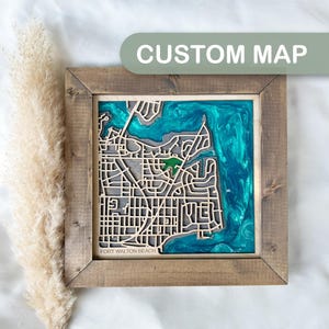 May include: A wooden map of Fort Walton Beach, Florida, with a blue and green epoxy resin inlay. The map is framed in a rustic brown wood frame.