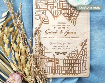 May include: A wooden wedding invitation with a custom map design. The invitation includes the names "Sarah & James", the date "October 5th, 2025", and the location "7035 Oakmont Dr, Santa Rosa, CA 95409". A small map is in the upper right corner.