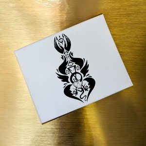 May include: Black and white illustration of a winged creature with a heart and a symbol in the center. The creature has a stylized design with intricate details.