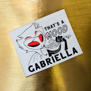May include: A white square with a black and red cartoon illustration. The illustration depicts a character eating from a bowl with the text "THAT'S A MOOD GABRIELLA" in black.