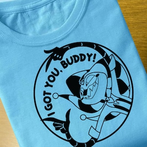 May include: A light blue t-shirt with a black and white graphic design of a cartoon character with the text "I got you, buddy!"