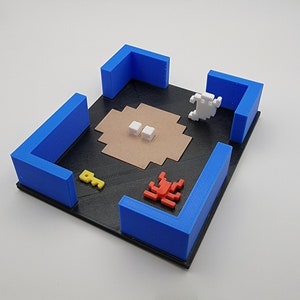 May include: A blue and black game board with a red scorpion, two white blocks, a yellow key, and a white figure. The board is made of cardboard and has a textured surface.