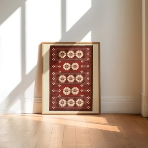 May include: A framed print of a red and white patterned rug with a geometric design. The rug is framed in a natural wood frame.