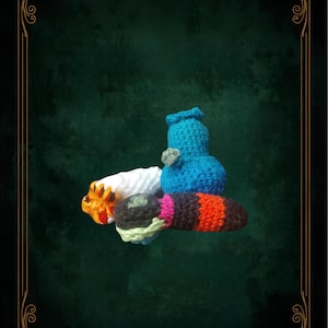 May include: A collection of handmade crochet items in various colors, including white, orange, blue, green, pink, and black. The items appear to be small, possibly decorative or functional, with a textured, handcrafted appearance. The background is a dark green with a decorative gold border.