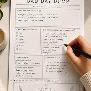 Könnte beinhalten: Ein weißes Papier mit dem Titel "BAD DAY DUMP" mit auszufüllenden Abschnitten zur Selbstreflexion. Der Text enthält Aufforderungen zu Auslösern, unzensierten Gedanken und Erinnerungen an die Selbstfürsorge. Eine Hand hält einen Stift und schreibt auf das Papier.