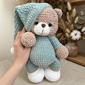 Puede incluir: Una taza de cerámica blanca con asa negra y el texto "But First, Coffee" en negrita negra. La taza se encuentra sobre un fondo borroso, sugiriendo un ambiente acogedor.