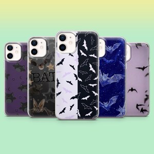 May include: Five smartphone cases with bat motifs. Designs include bat silhouettes, stars, and the word "BAT". The cases are in shades of purple, black, white, and blue. These cases are designed to protect a mobile phone.
