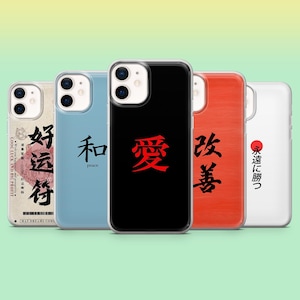 Può includere: Una collezione di cinque custodie per telefoni con caratteri giapponesi. Le custodie sono in vari colori, tra cui nero, blu e bianco. Ogni custodia presenta un carattere diverso in rosso o nero.