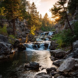 Peut inclure: Un paysage pittoresque avec une cascade dévalant une gorge rocheuse. L'eau est claire et reflète la lumière du soleil. Des arbres et du feuillage entourent la cascade, avec le soleil couchant en arrière-plan, créant une lueur dorée et chaleureuse.