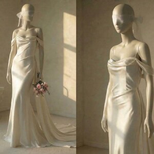 A mannequin wearing a long, flowing white wedding dress with a train, holding a bouquet of flowers.
