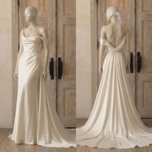 A mannequin wearing a long, off-the-shoulder white wedding dress with a flowing train, displayed in front of a wooden door.