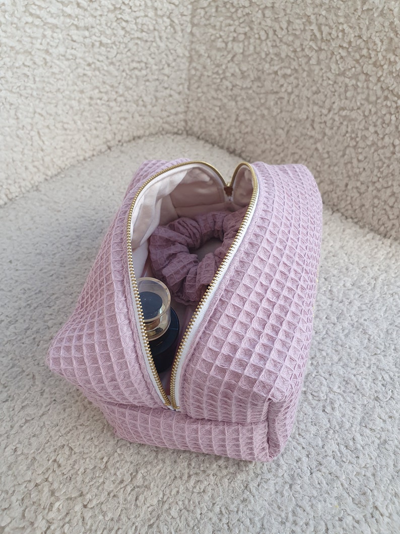 Close-up of the zipper pull on the eco-friendly makeup bag, highlighting its stylish and functional design. High-quality golden metal zipper closure detail on the eco-conscious waffle makeup bag, showcasing secure design.