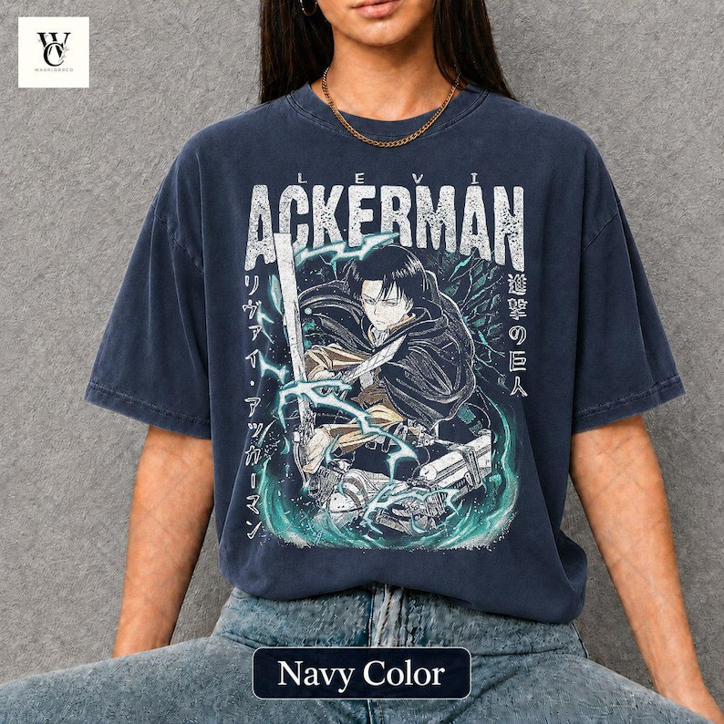 Pu&ograve; includere: T-shirt blu navy con grafica di un personaggio con una spada, il nome "ACKERMAN" in bianco e testo giapponese. La maglietta ha un aspetto vintage e il testo "Navy Color" &egrave; in basso.