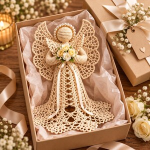 May include: A crocheted angel figurine in a beige yarn with intricate lace-like wings and a skirt. The angel features a halo of small white beads, holds a bouquet of cream-colored fabric roses, and is presented inside a gift box with tissue paper.