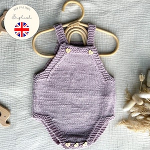 May include: A lilac-colored knitted baby romper with wooden button details, hanging on a wooden hanger. The romper has a round neckline and straps. A wooden elephant toy and a wooden teething ring are also visible. The text "PDF Pattern English" is in a circle.