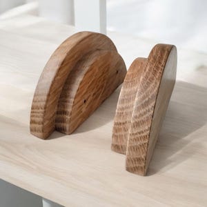 May include: Two wooden half-circle shelf brackets with a natural wood finish. The brackets are made of solid wood and have a smooth, rounded edge.