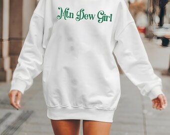 Puede incluir: Sudadera blanca con el texto "Mtn Dew Girl" en letras verdes cursivas.