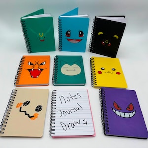 May include: A collection of spiral-bound notebooks with colorful covers featuring cartoon character designs. The notebooks are in various colors, including green, blue, orange, teal, yellow, beige, pink, and purple. One notebook has the text "Notes Journal Draw".