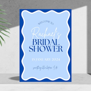 Puede incluir: Un cartel de ducha nupcial azul y azul claro con el texto "Bienvenido a Rachel's Bridal Shower 15 de enero de 2024 something blue before I do".