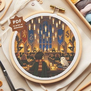 May include: A circular wooden embroidery hoop containing a cross-stitch pattern of a grand hall with floating candles, house banners, and students at tables. A white owl sits on a stack of books in the foreground. A brown star-shaped tag reads PDF to print or download.