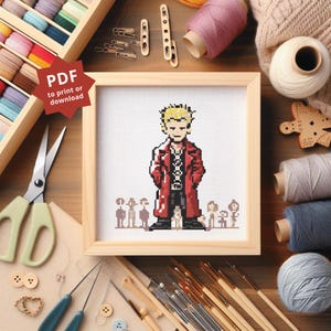 Könnte beinhalten: Ein gerahmtes Kreuzstichbild mit einer pixeligen Figur in einem roten Mantel und blonden Haaren, umgeben von kleineren Figuren. Der Rahmen ist aus hellem Holz. Handwerksmaterialien wie Scheren, Fäden und Pinsel umgeben das Bild.