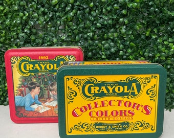 May include: Two vintage Crayola collector's tin boxes. One is red with a Christmas scene and the year 1992. The other is green and yellow, with "Collector's Colors" and "Limited Edition" text. Both feature the Crayola logo.